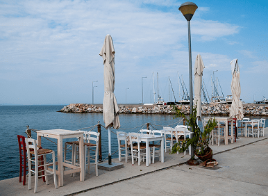 Empty seaside cafe tables by marina